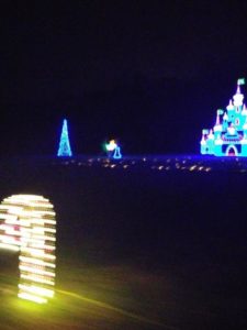 Christmas lights, On forwad is a white candy cane, towards the back a little to the right is a blue tree, center is a princess leaning over kissing a frog. On the right is a blue castle cropping off the right side of the castle