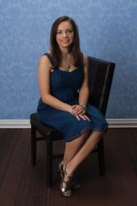 Katie Proia sitting on a chair in a blue dress
